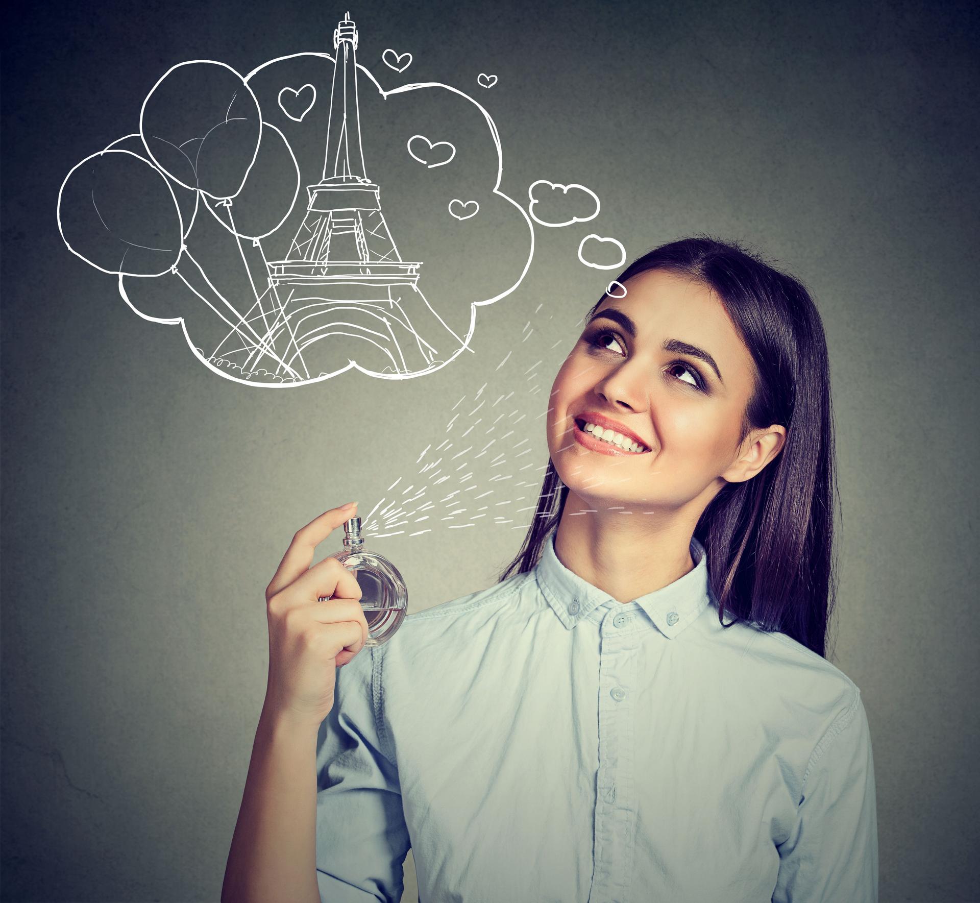 woman holding bottle of perfume and smelling aroma