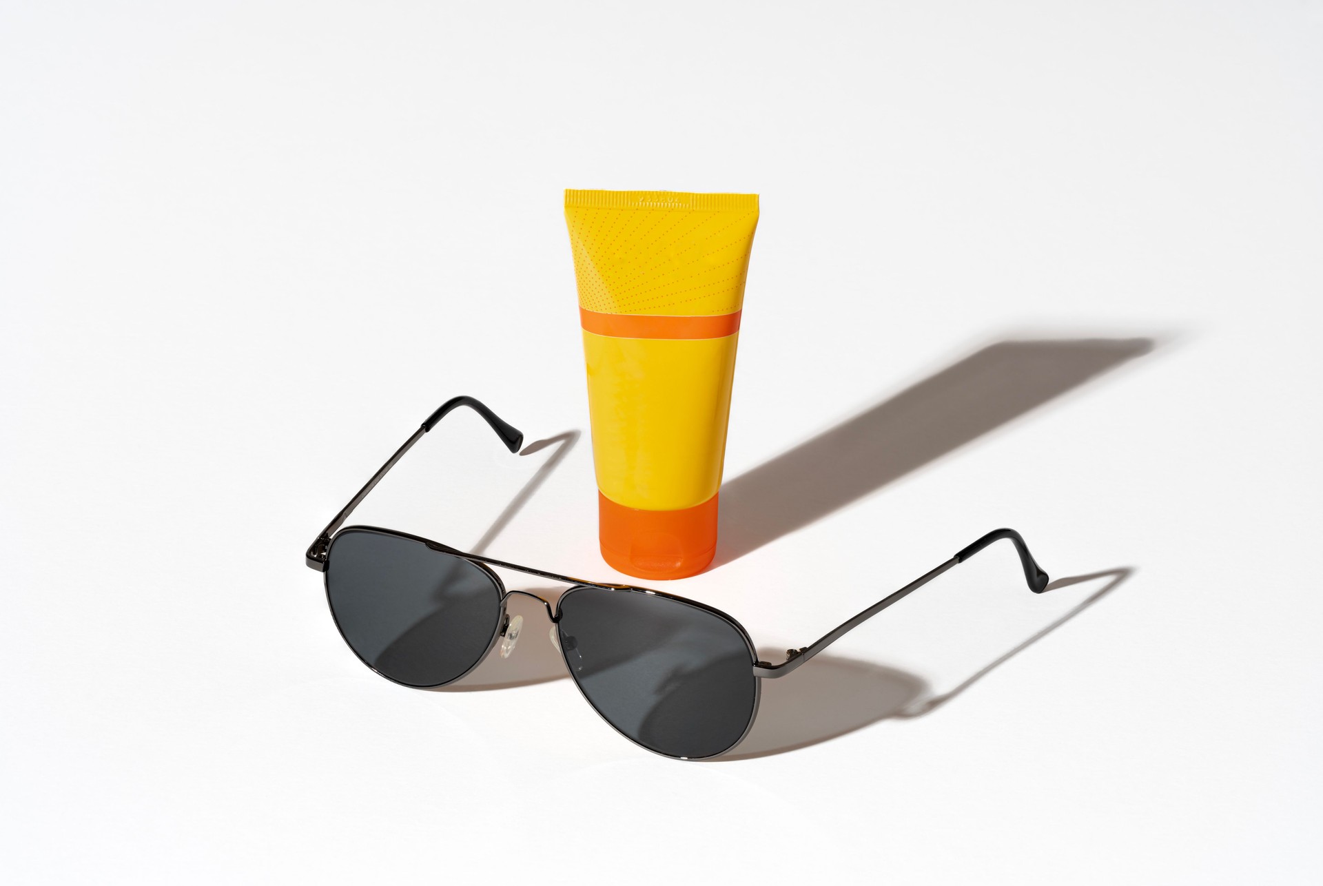 Paris, France - 07 12 2022: still life. Studio shot of sunglasses and a yellow sunscreen tube